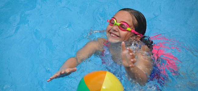 Girl Wearing Goggles Playing in Pool with Ball